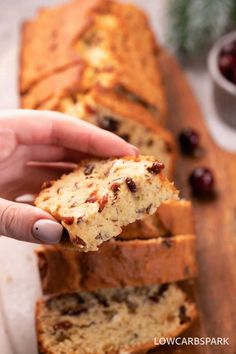 a person holding a piece of bread with raisins on it next to some cranberries