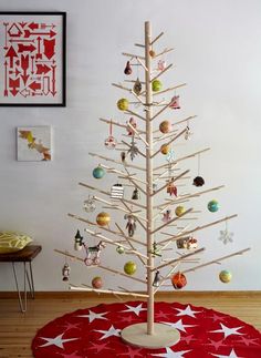 a wooden christmas tree with ornaments on it in a room next to a red and white rug