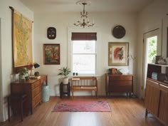 a living room filled with furniture and paintings on the wall next to a wooden floor