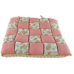 a pink and white cushion with flowers on the front, sitting on top of a pillow