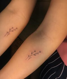 two women with matching tattoos on their arms, one has a flower and the other has an arrow