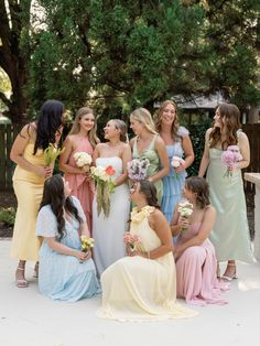 a group of women standing next to each other in dresses and holding bouquets on the ground