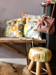 a dog laying on the floor in front of a table with pillows and stools