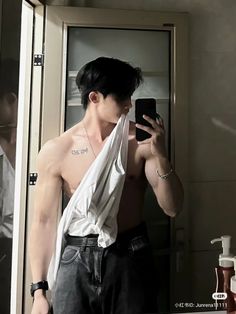 a shirtless man taking a selfie in the mirror with his cell phone and towel wrapped around his neck