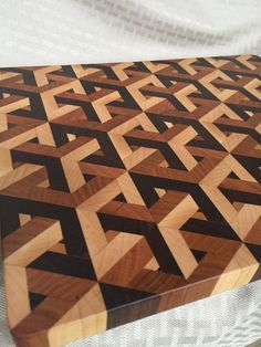 a wooden cutting board sitting on top of a white cloth covered tablecloth with black and brown designs