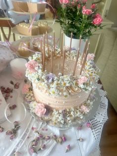 there is a cake with flowers on it and candles in the middle, sitting on a table