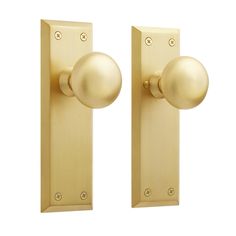 two gold door knobs on the side of a white wall and one has a round handle