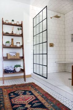 a white tiled bathroom with shelves and rug