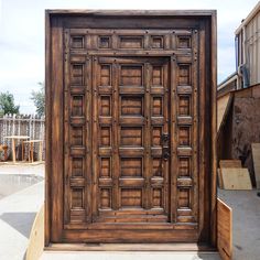 a large wooden door sitting in the middle of a cement area next to a building