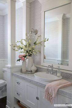 a white bathroom with pink flowers in a vase