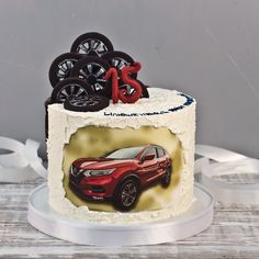 a birthday cake with an image of a red car and wheels on the top tier