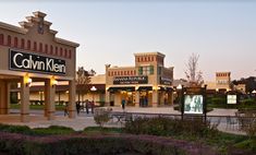 people are walking in front of the store called calvinn kilni at dusk