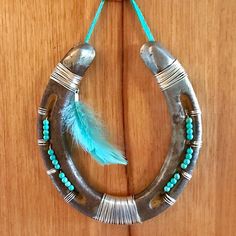 an old horseshoe with turquoise beads and feathers hanging on a wooden door