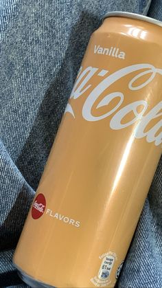 a can of coca - cola sitting on top of someone's blue jean pants