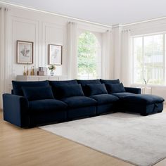 a living room with a large blue couch and white rugs on the hardwood floor