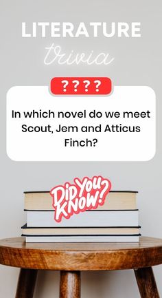 a stack of books sitting on top of a wooden table next to a white wall