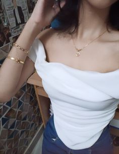 a woman in a white top is talking on her cell phone while wearing gold bracelets