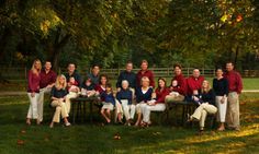 a large group of people are posing for a photo in the grass with trees behind them