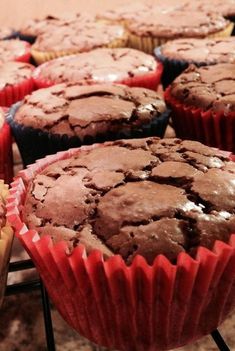 chocolate muffins sitting on top of a rack next to other cupcakes