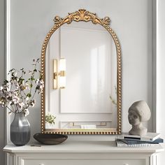 a mirror sitting on top of a dresser next to a vase with flowers in it