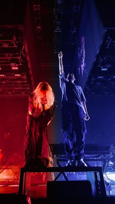 two people standing on stage with their arms in the air