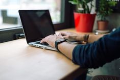 a person sitting at a table with a laptop computer on their lap and holding a mouse