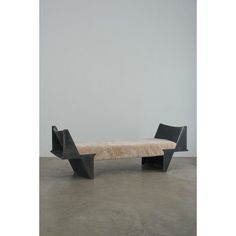 a black bench sitting on top of a cement floor next to a white wall in an empty room