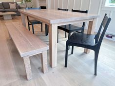 a wooden table with two black chairs next to it and a bench in the middle