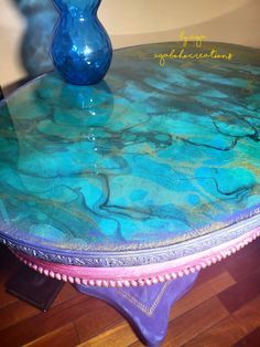 a blue vase sitting on top of a table next to a purple base and wood floor