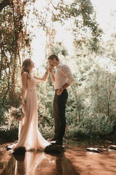 a man and woman standing next to each other in front of trees with red light