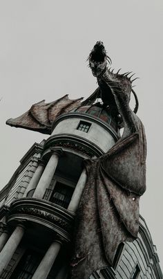 a tall building with a dragon statue on the top of it's head and wings