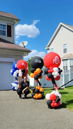 a man kneeling down next to balloons in front of a house