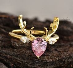 a gold ring with a pink heart shaped stone and two white diamonds on the side