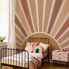 a bedroom with a bed, dresser and wall mural in the shape of a sun