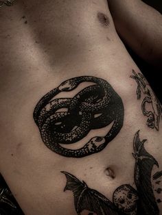 a black and white photo of a man's stomach with a snake tattoo on it