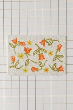 a white tile wall with orange and yellow flowers painted on the bottom part of it