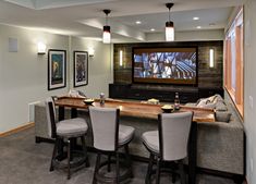 a large entertainment room with bar seating and tv on the wall, in front of two couches