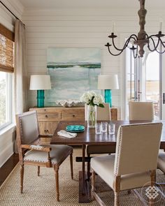 a dining room table with chairs and a chandelier in front of the window