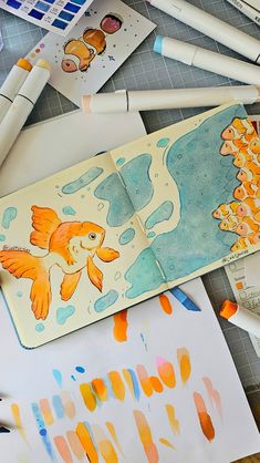 an open notebook with watercolors and fish on it