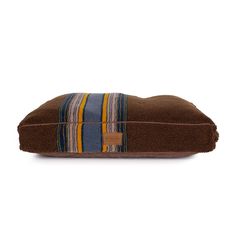 a brown dog bed with blue, yellow and orange stripes on the front is shown