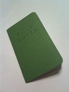 a green notebook with the words help nots written on it sitting on a white surface