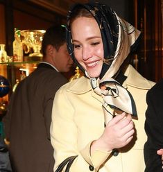 a woman with a scarf around her head smiles at the camera while standing in front of other people