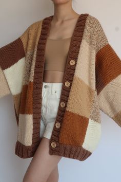 a woman wearing a brown and white striped cardigan sweater with her hands on her hips