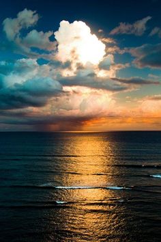 the sun is setting over the ocean with clouds in the sky and waves on the water