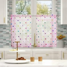 a kitchen with white cabinets and polka dot curtains in pink, green, yellow and blue