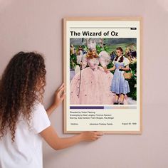 a woman is holding up a poster to show the wizard of oz