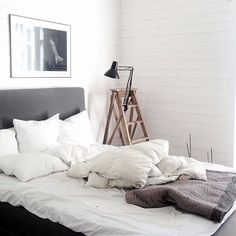 an unmade bed with white pillows and blankets on it in a room next to a window