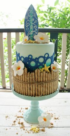 there is a blue and white cake with flowers on the top, sitting on a table