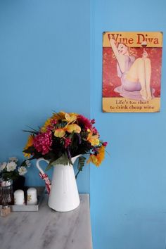 a vase with flowers sitting on a table next to a sign that says wine diya