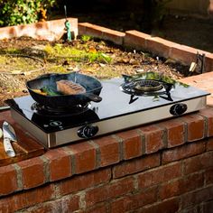 a stove top sitting on top of a brick wall